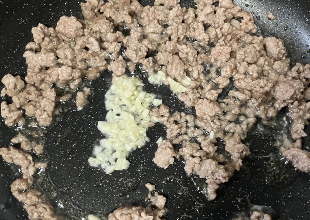 炒めた挽肉に、にんにくを加えて炒めている画像